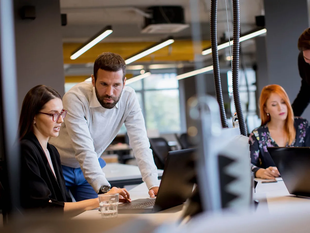 Des collègues travaillent ensemble sur un ordinateur portable dans un open space